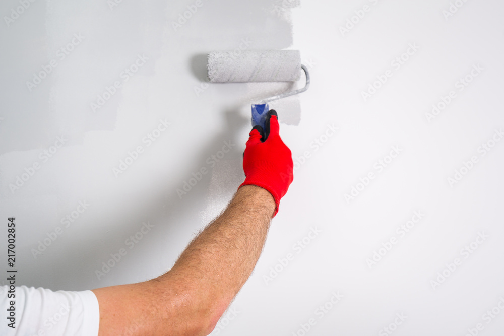 Painter hand painting a wall with paint roller