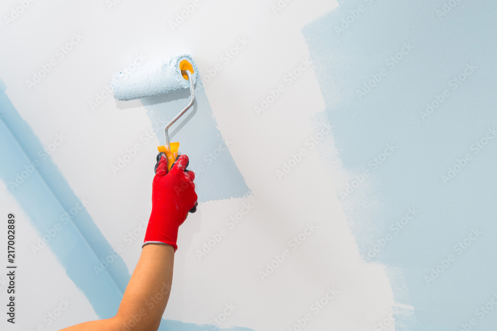 Painter hand painting a wall with paint roller