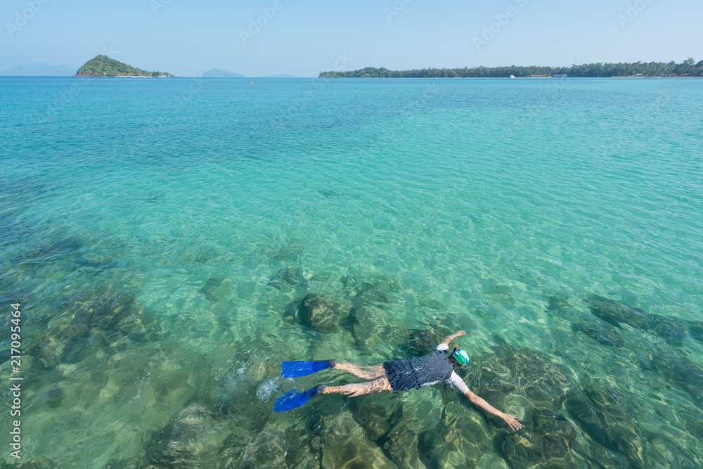 游客在泰国普吉岛热带度假胜地附近的水晶绿松石水中浮潜。夏天，瓦卡蒂