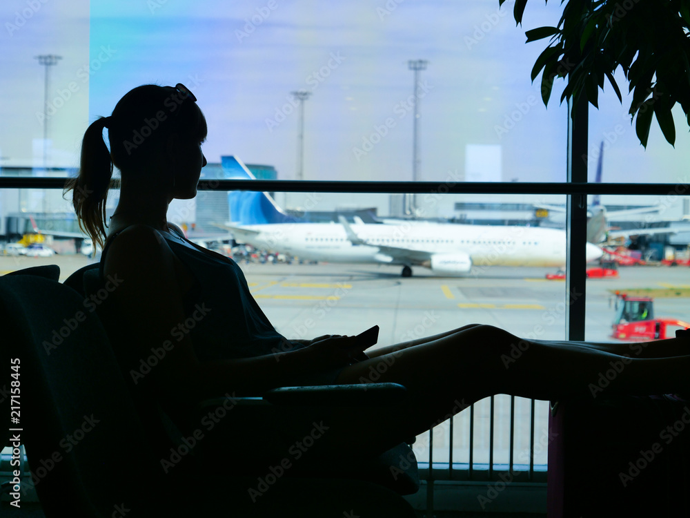 CLOSE UP: Unknown young woman holding her cell phone while looking at runway.