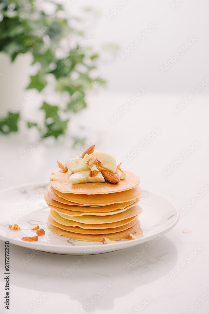 一堆美味的煎饼，里面有巧克力、蜂蜜、坚果和香蕉片，放在石头背上的盘子里