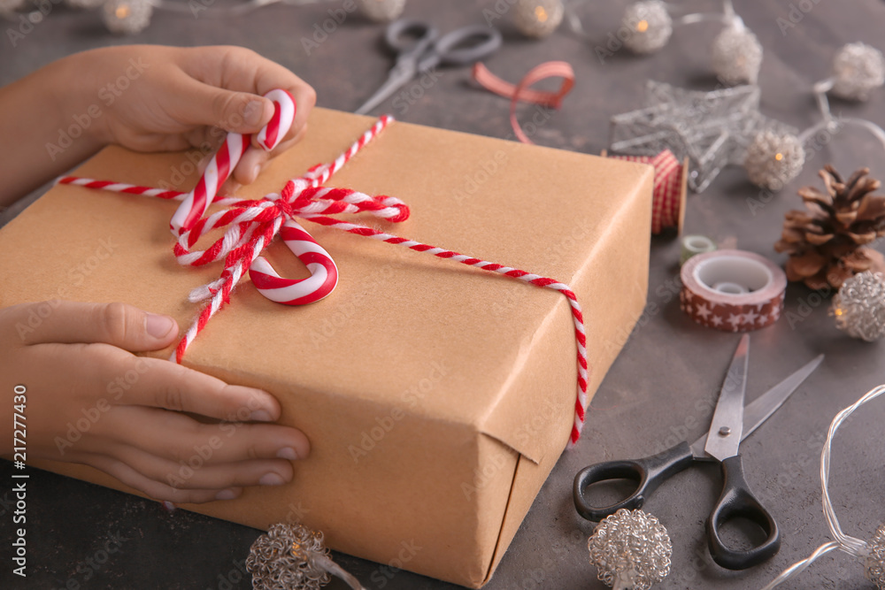 Child wrapping Christmas gift at table, closeup