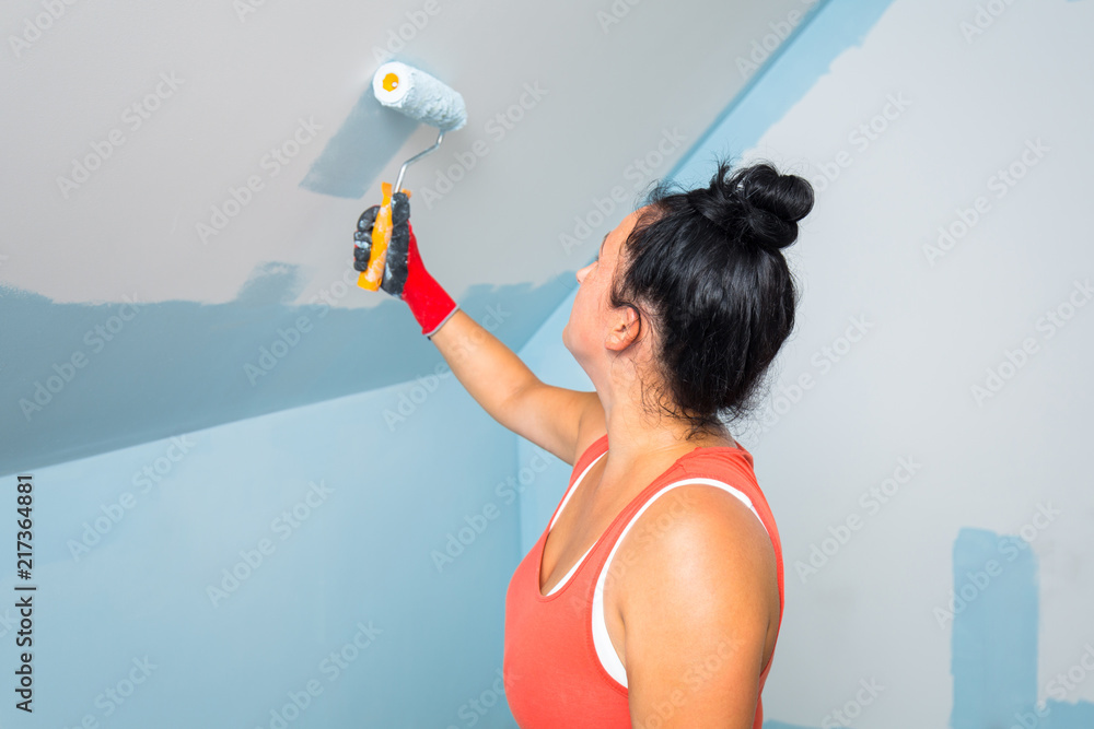 Woman at painting a room with paint roller