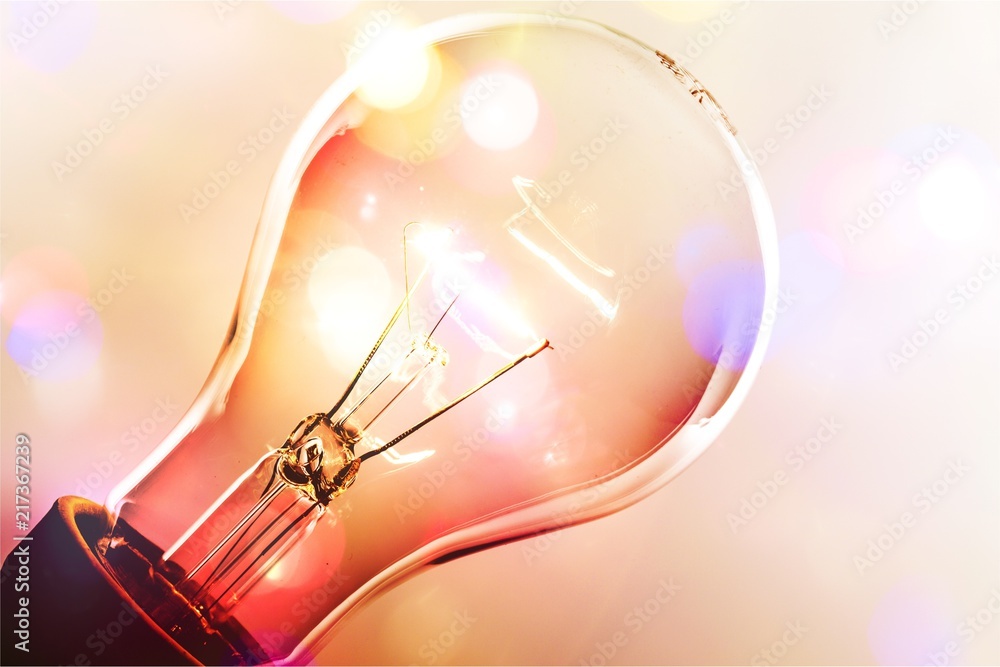 Glowing glass light bulb on colored background