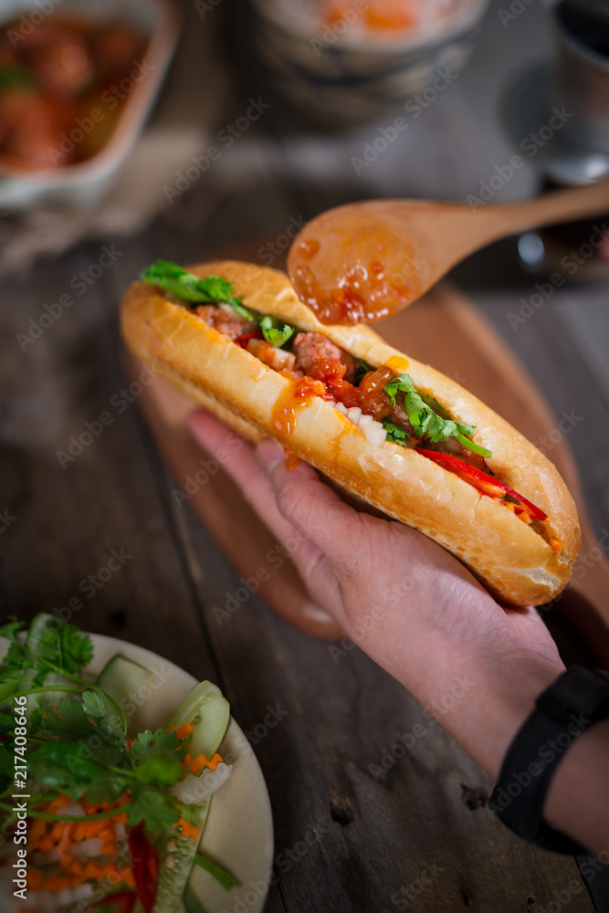 Vietnamese sandwich bread with meatballs in tomato sauce and radish, carrot pickle, cucumber, corian