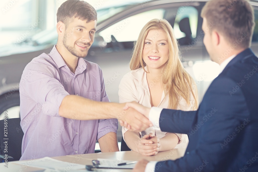 Happy couple with car dealer