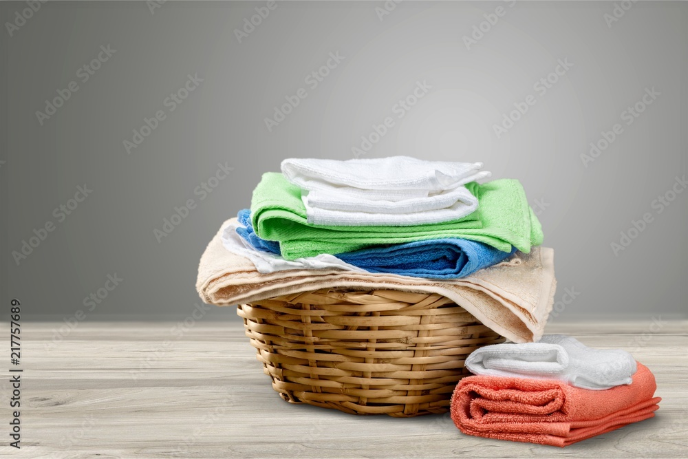 Laundry Basket with colorful towels on background