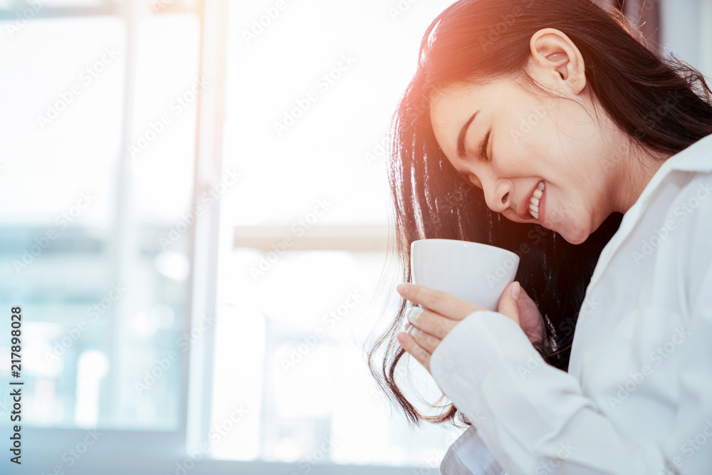 Asian girl who just wake up in the morning as relaxed. She opened the window to receive the light of