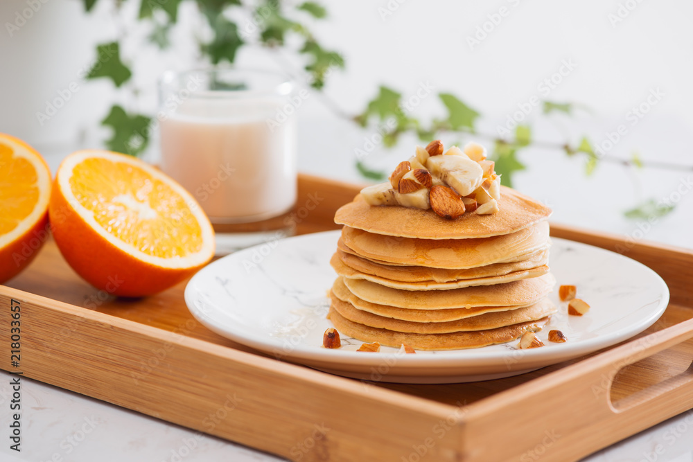 一堆美味的煎饼，里面有巧克力、蜂蜜、坚果和香蕉片，放在石头背上的盘子里