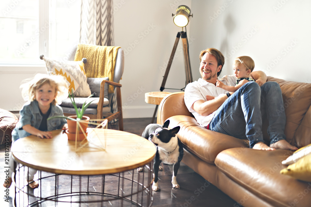 Young father with baby daughter and son on sofa at home