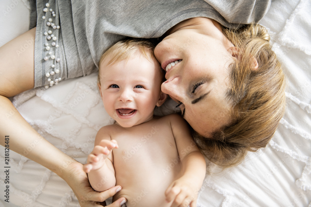 Mother and baby girl on a white bed