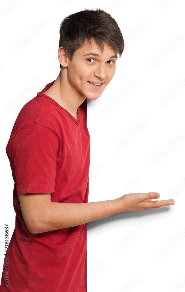 Young man looking around a corner and showing off a blank sign