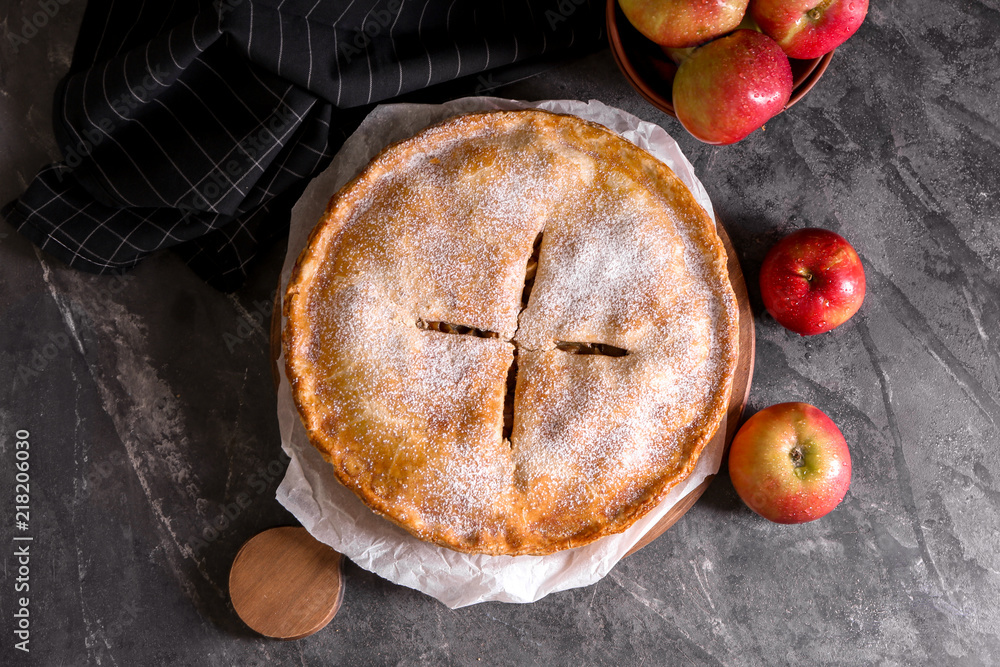 Board with delicious apple pie on dark table