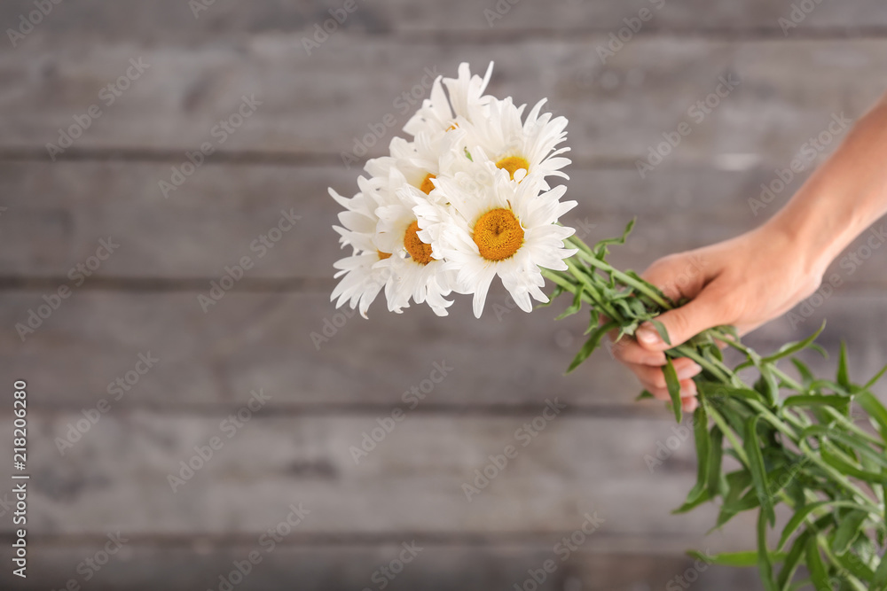 木质背景上手持美丽迷彩花的女人