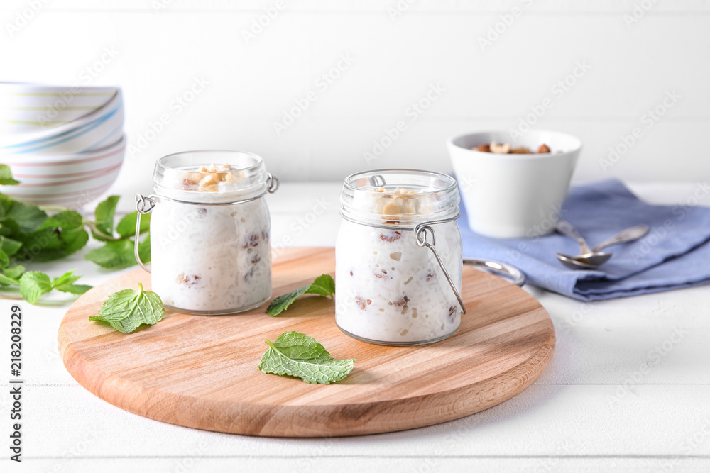 Glass jars with delicious rice pudding and nuts on board