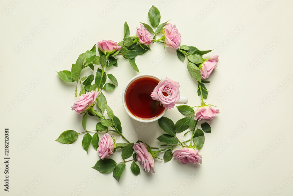 Beautiful rose flowers with cup of tea on white background, top view