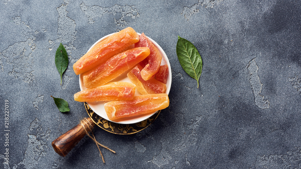 Dried sweet papaya sticks. Candied fruits on gray background. Top view.