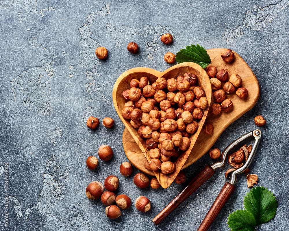 Hazelnuts with nutcracker on gray background. Top view of nuts.