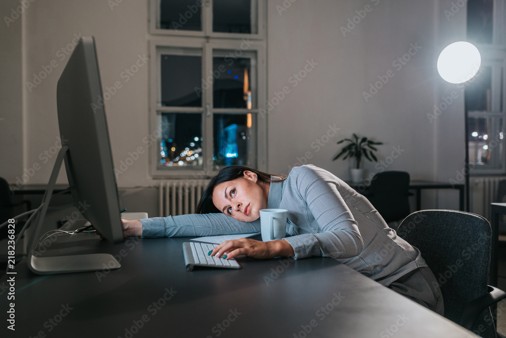 Overworked woman lying on the office desk while working.