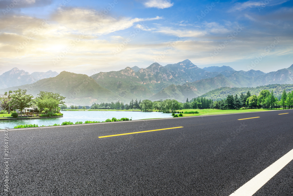 空旷的柏油公路和日落时的青山自然景观