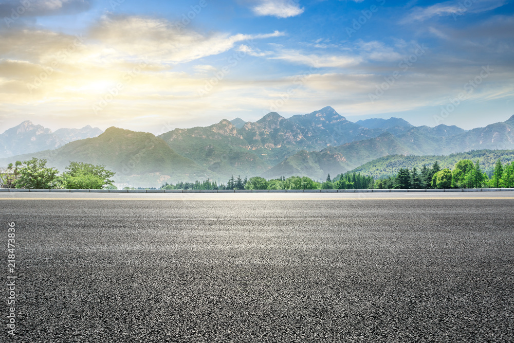 空旷的柏油公路和日落时的青山自然景观