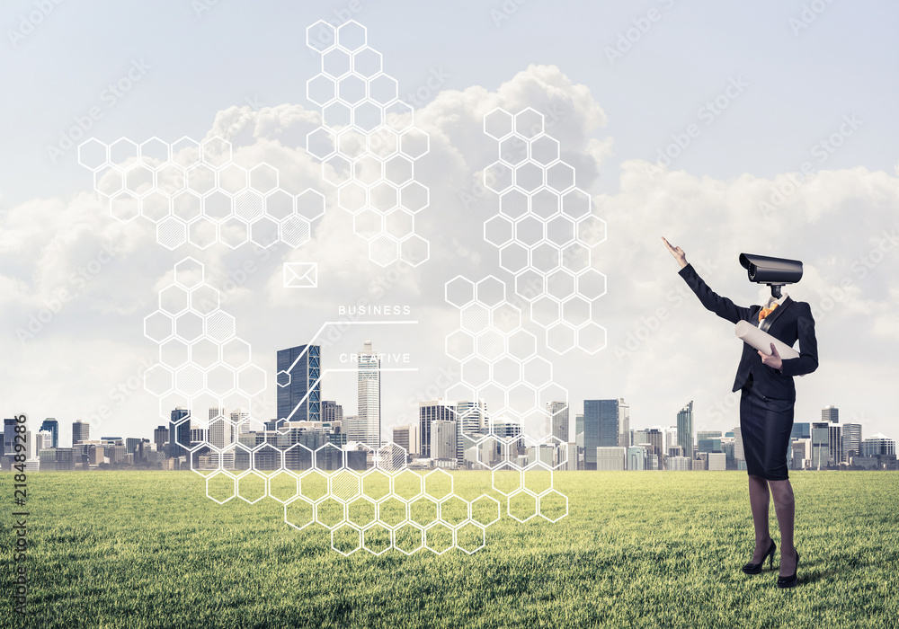 Camera headed woman standing on green grass against modern citys