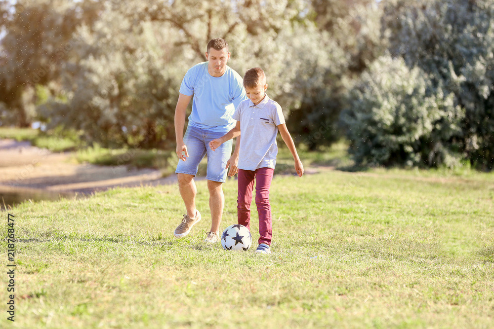 Father with son playing football outdoors