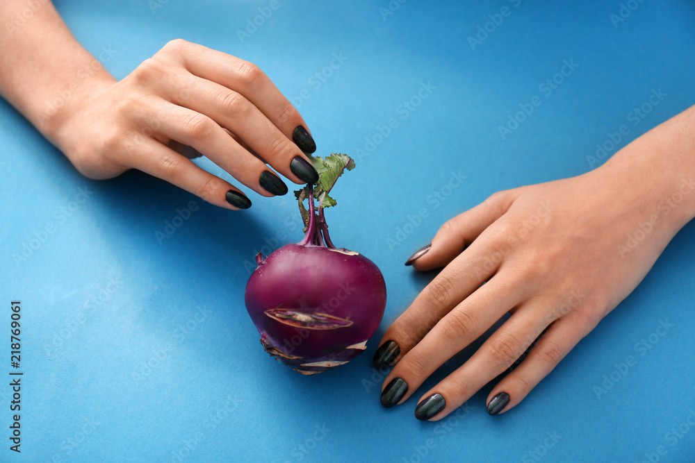 Woman with stylish manicure holding turnip on color background