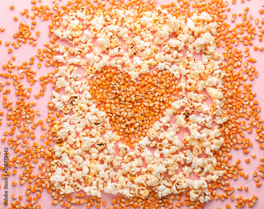 Heart made of delicious popcorn and kernels on color background