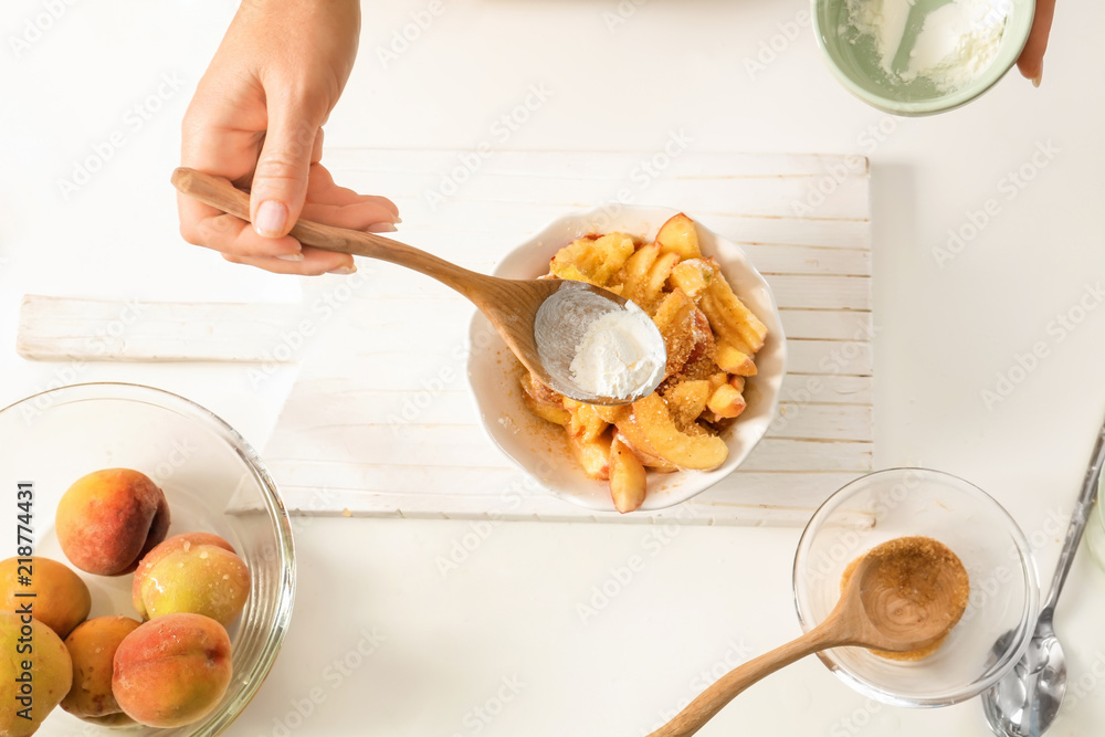 Woman preparing peach galette on light table