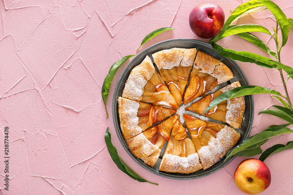 Plate with delicious peach galette on color table