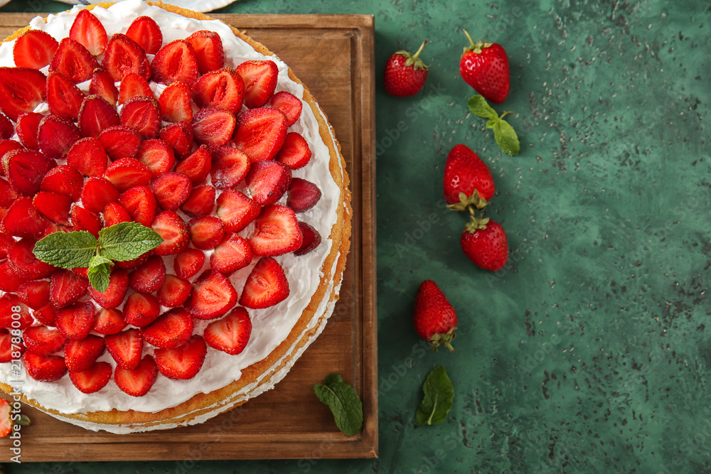 Delicious cake with strawberries on green table