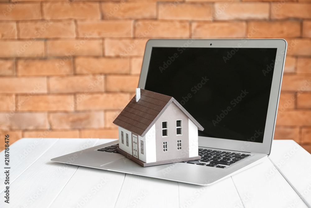 House model with laptop on table. Mortgage concept