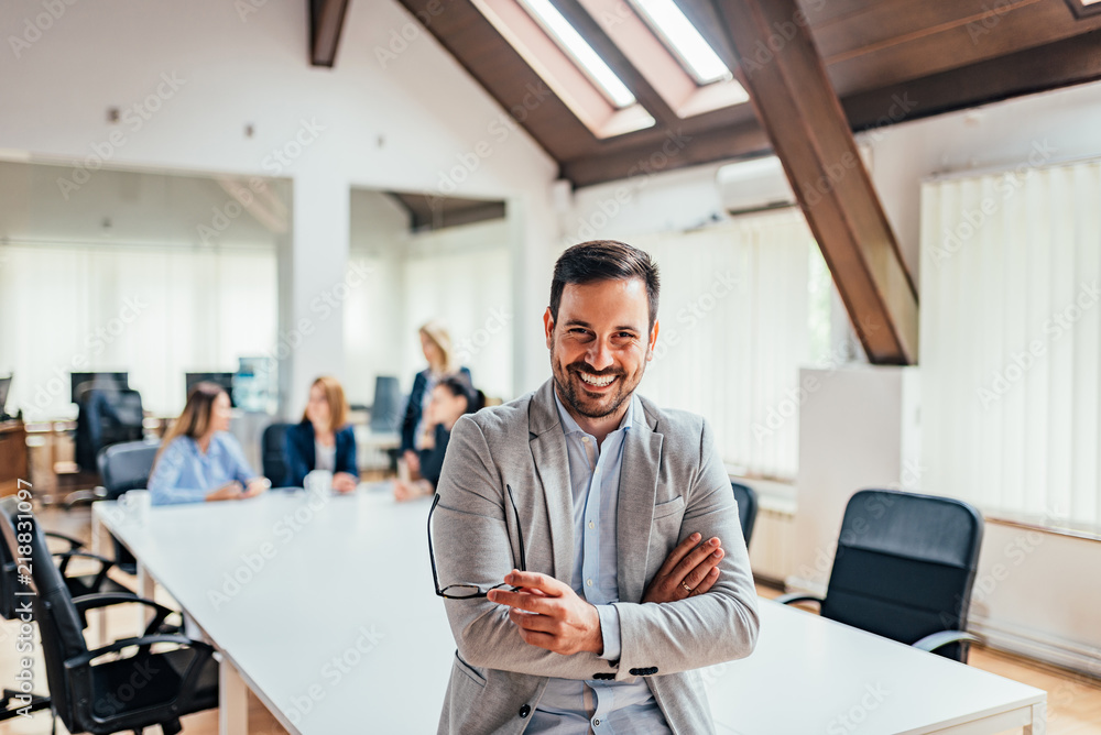 Portrait of a smiling handsome businessman with crossed arms in a meeting room.