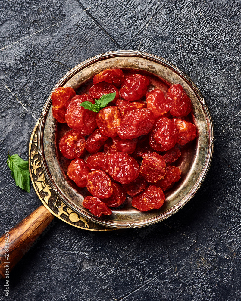 Candied cherry tomatoes on black background. Top view of dessert.