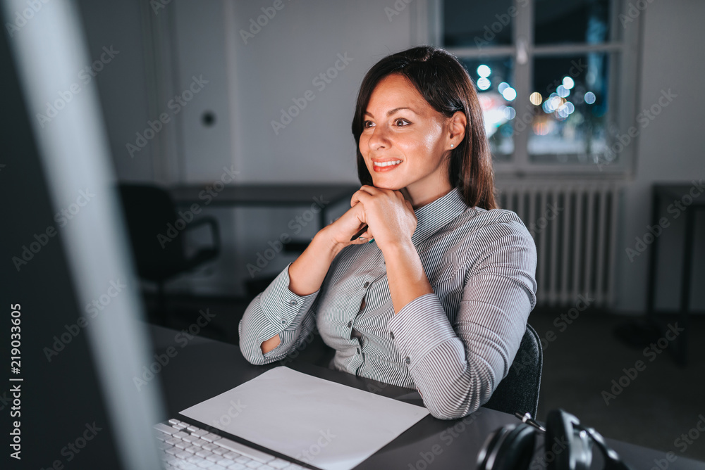 Close-up image of smiling businesswoman while working late at night.