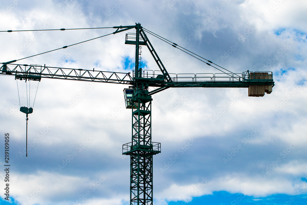 Construction cranes on the construction site against the blue sky and clouds