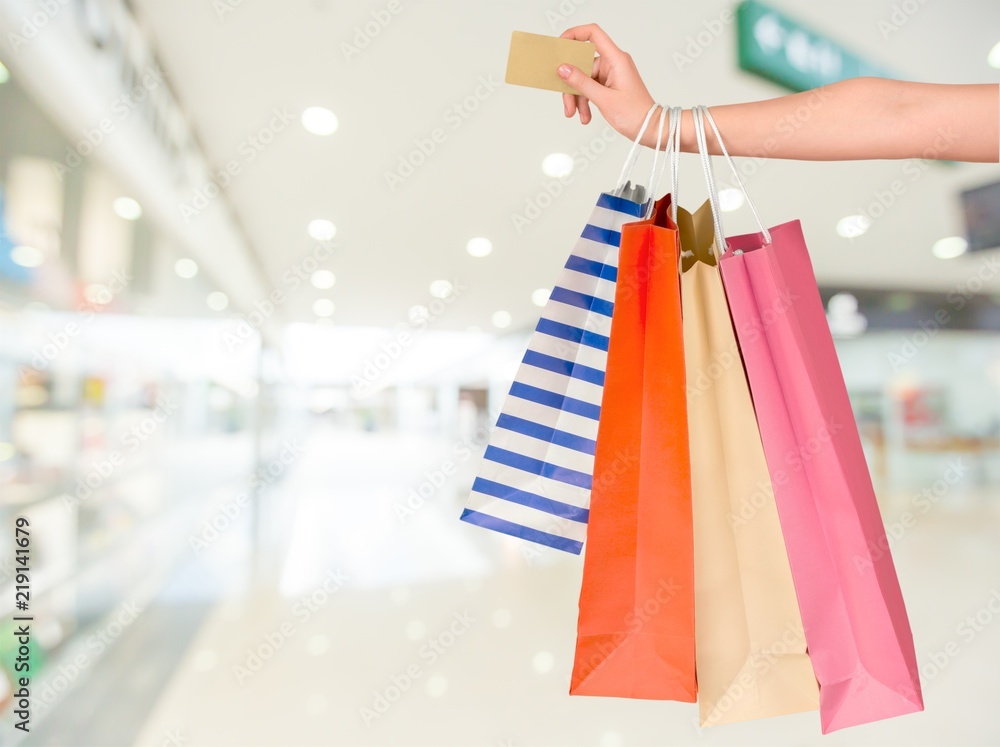 Woman with shopping bags and card on mall background