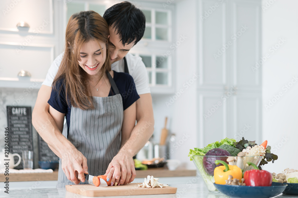 厨房里年轻漂亮的夫妇。一家两口在准备食物。夫妇在做美味的沙拉。烹饪