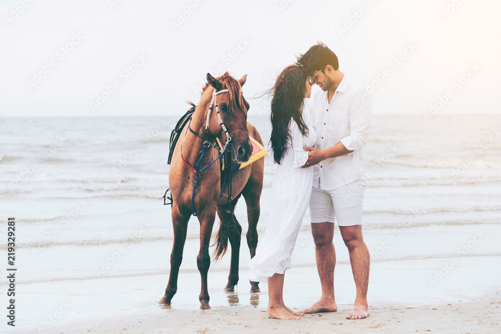 Young couple goes horse riding on tropical beach.