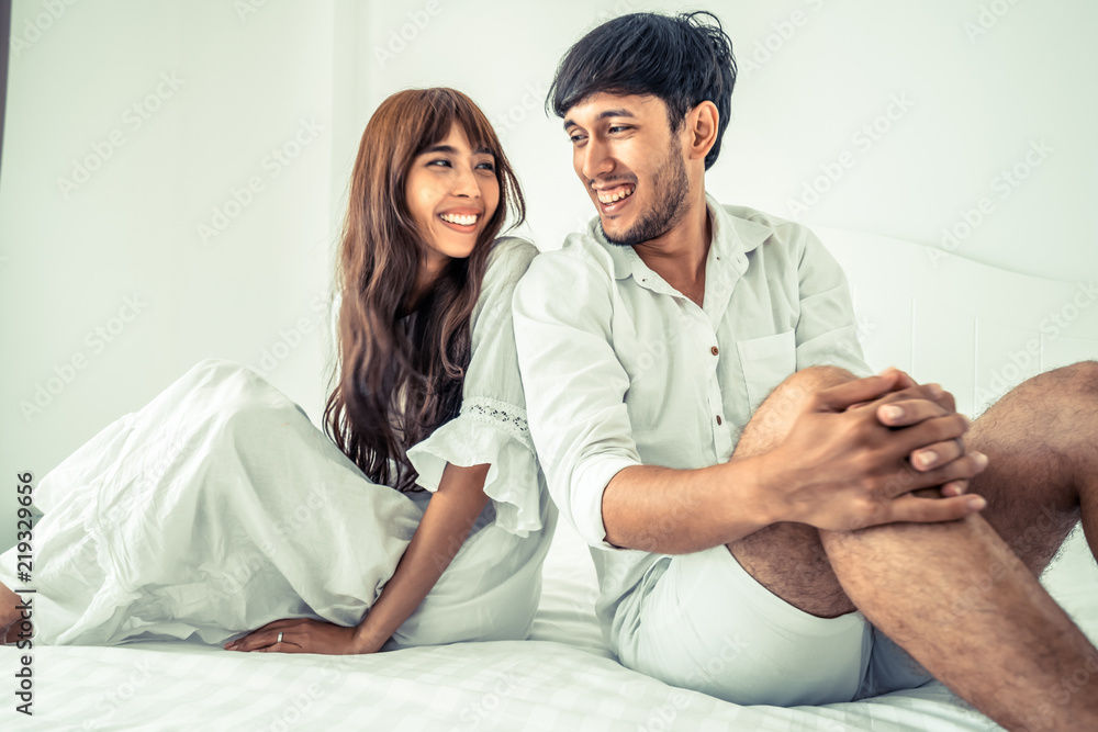 Happy young couple relaxing in the home bedroom.