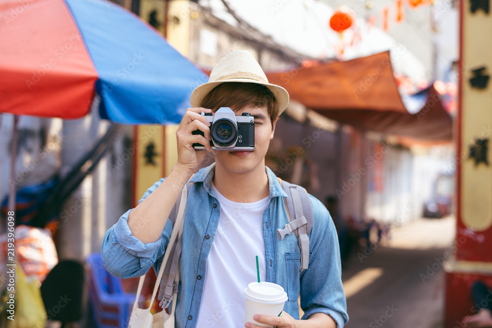 年轻的亚洲男子旅行者在街头市场购物