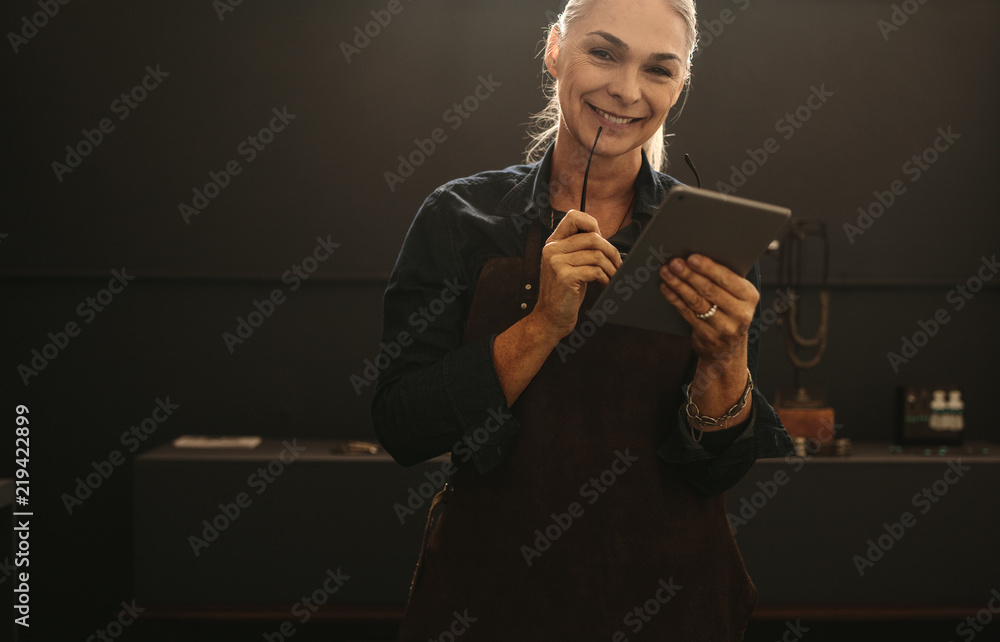 Female goldsmith with tablet pc at workshop