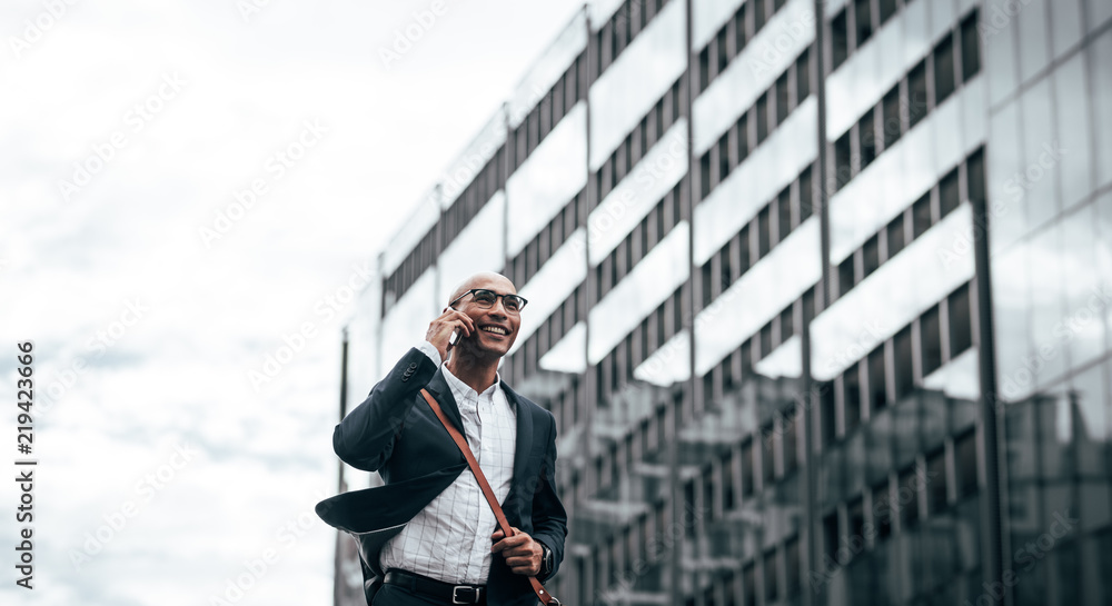 Businessman talking on mobile phone walking outdoors