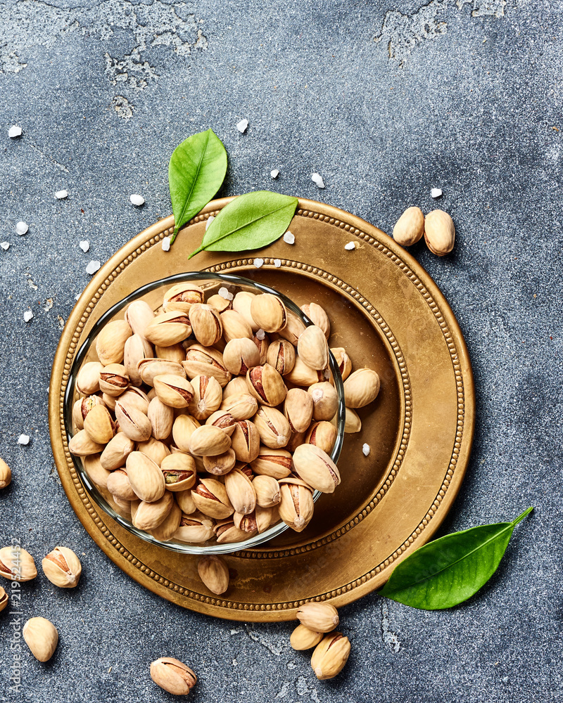 Salted Pistachios with green leaves. Top view of snacks.