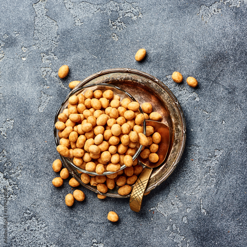 Spicy coated fried peanuts on gray background. Top view of snacks and nuts.