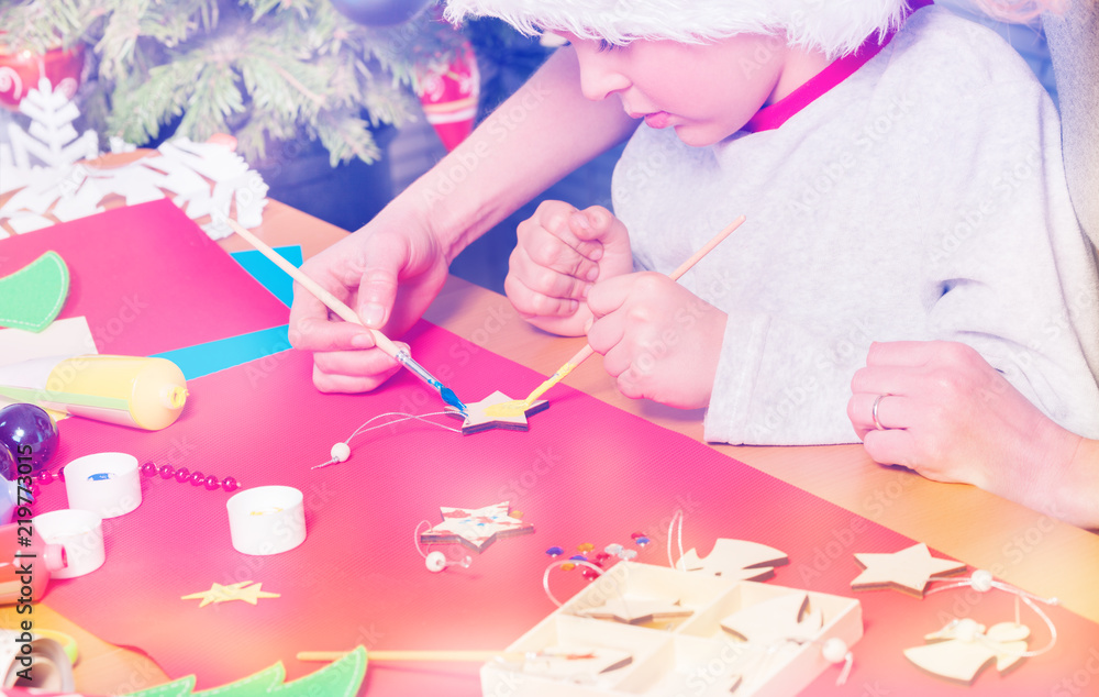 Boy decorates Christmas star together with his mom