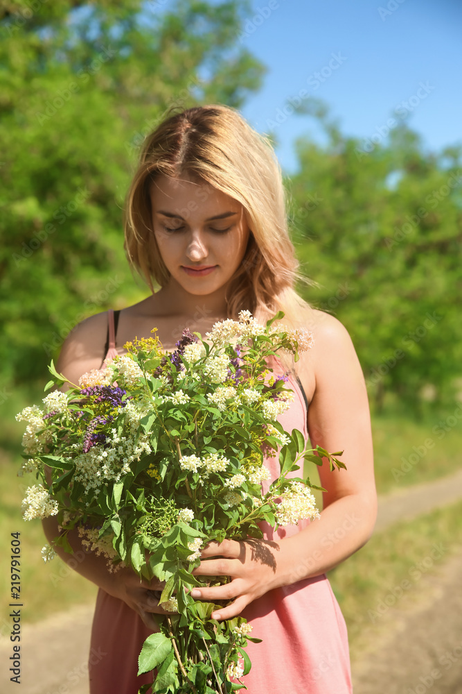 Young woman holding bouquet of beautiful flowers outdoors