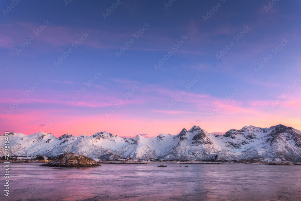 美丽的雪山和多彩的天空在夜晚倒映在水中。冬季景观与