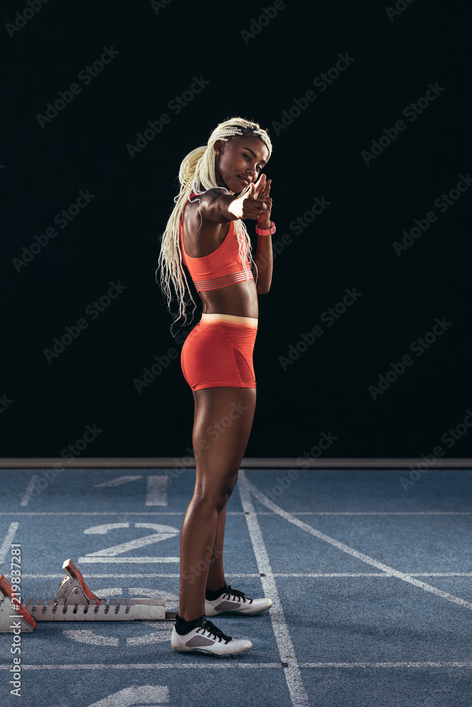 Female athlete in a cheerful mood standing on a running track